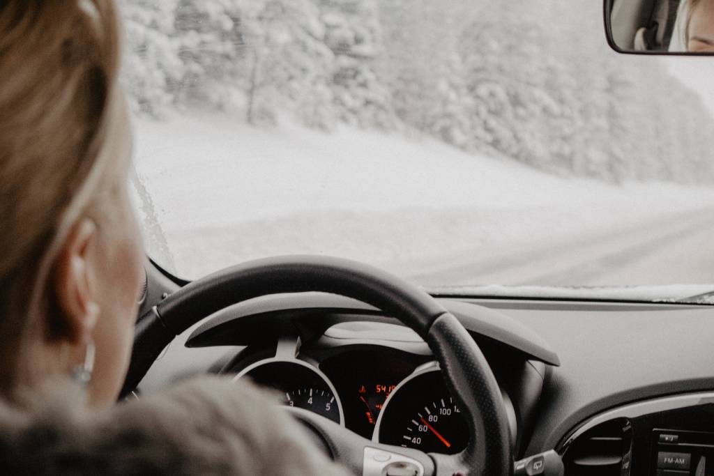 kobieta jedzie autem po zaśnieżonej drodze